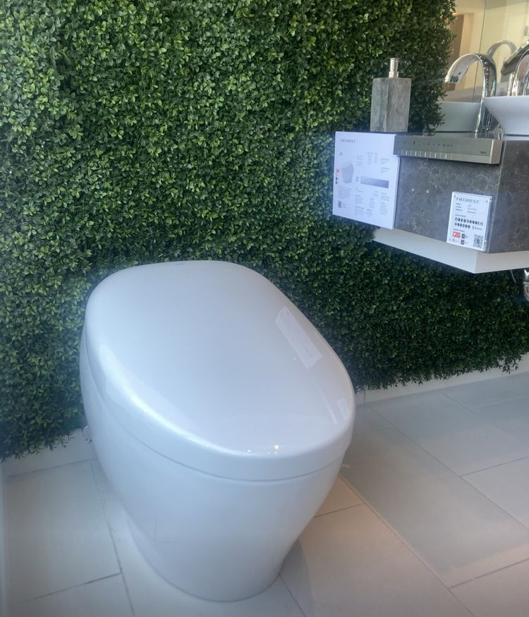 NEOREST toilet on display in front of greenery wall